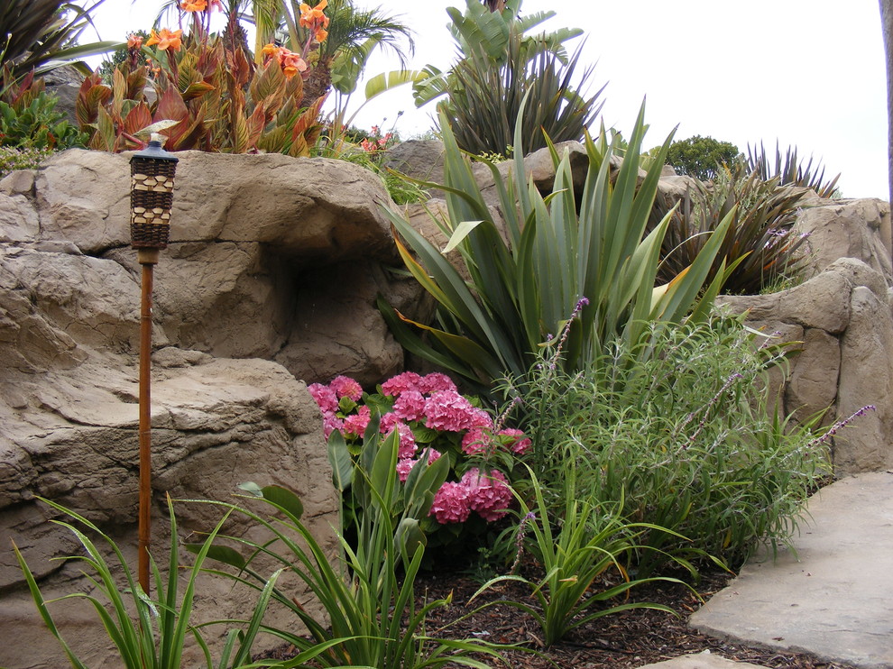 Design ideas for a rustic backyard retaining wall landscape in Orange County.