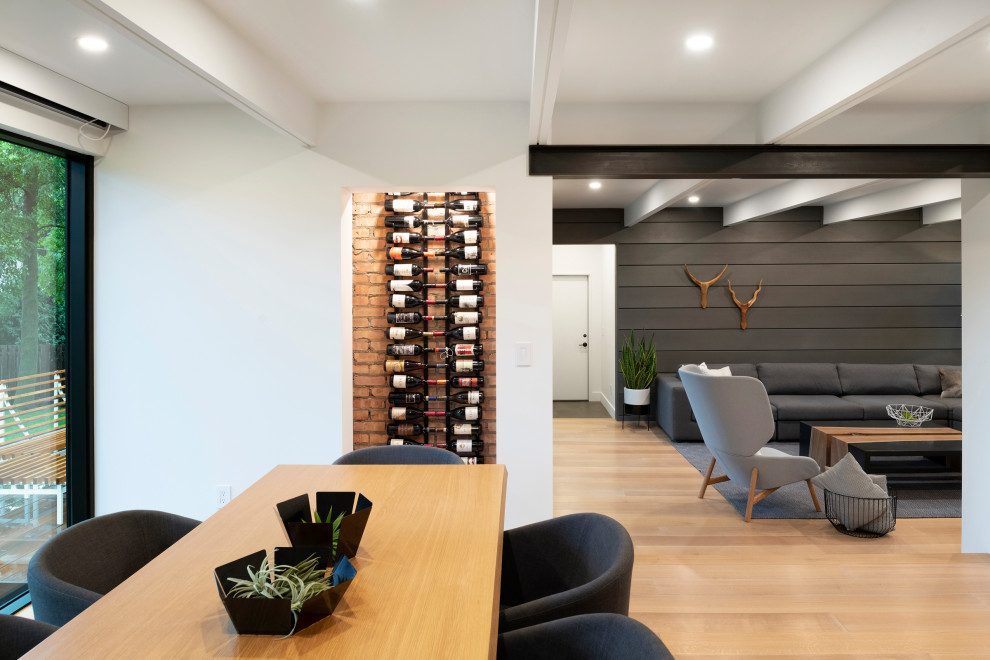 This is an example of a midcentury wine cellar in Minneapolis with light hardwood floors and display racks.