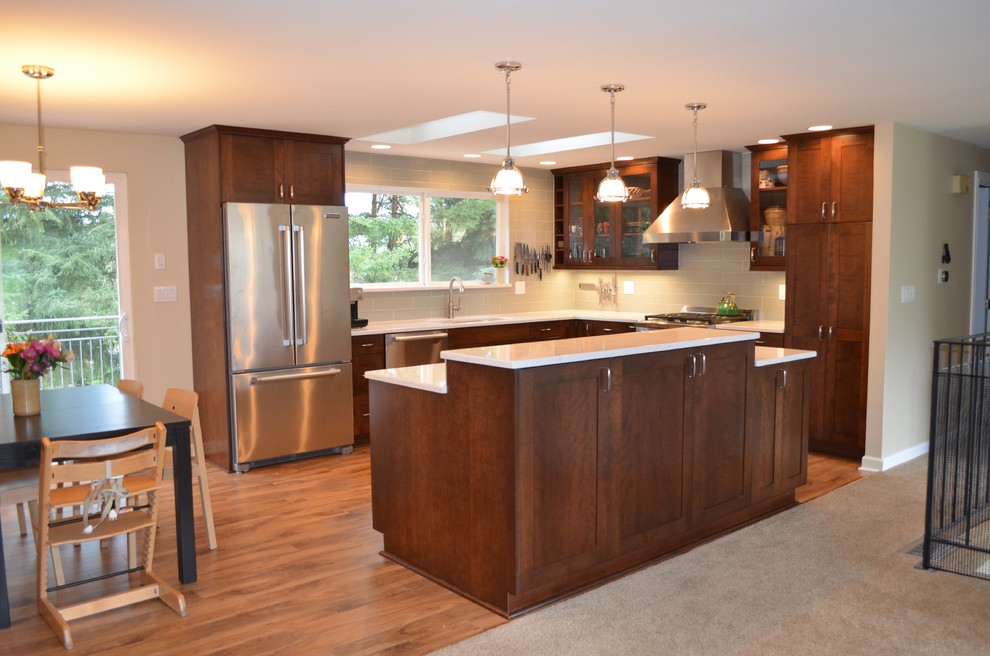 Inspiration for a mid-sized transitional l-shaped medium tone wood floor and brown floor open concept kitchen remodel in Seattle with an undermount sink, shaker cabinets, dark wood cabinets, quartz countertops, stainless steel appliances, an island, gray backsplash and subway tile backsplash