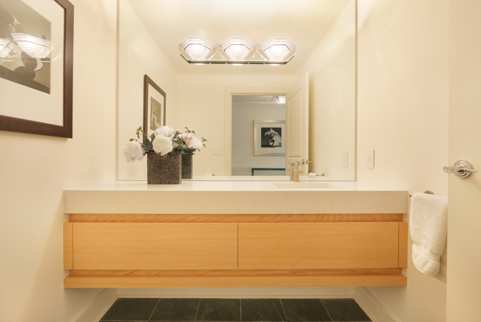 Small modern powder room in Atlanta with flat-panel cabinets, light wood cabinets, an undermount sink, solid surface benchtops, white benchtops and a floating vanity.