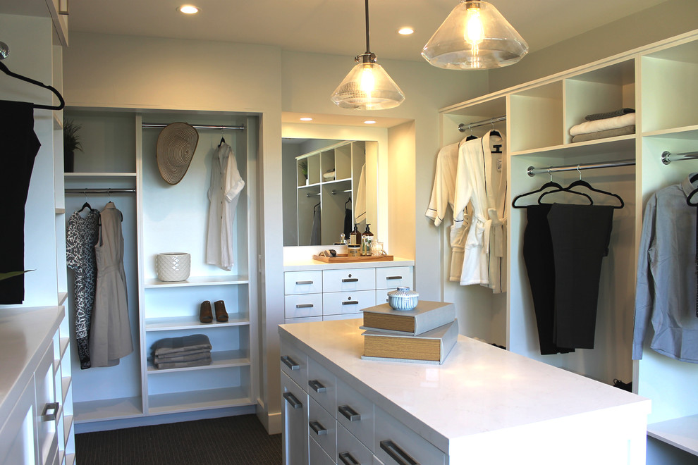 This is an example of an expansive modern gender-neutral walk-in wardrobe in Los Angeles with open cabinets, white cabinets, carpet and grey floor.