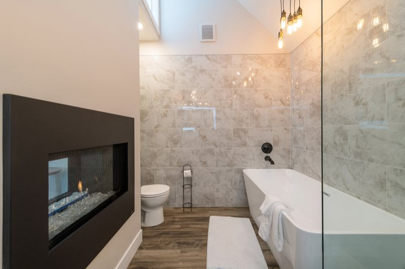 Photo of a small modern master bathroom in Salt Lake City with shaker cabinets, grey cabinets, a freestanding tub, a corner shower, a one-piece toilet, beige tile, marble, beige walls, laminate floors, an undermount sink, engineered quartz benchtops, multi-coloured floor, a sliding shower screen, white benchtops, a double vanity, a built-in vanity and vaulted.