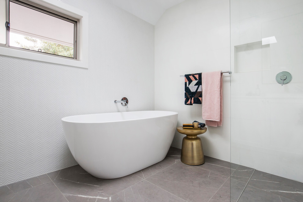 This is an example of a large contemporary master bathroom in Sydney with shaker cabinets, white cabinets, a freestanding tub, an open shower, a wall-mount toilet, white tile, porcelain tile, white walls, porcelain floors, an integrated sink, engineered quartz benchtops, grey floor, an open shower and white benchtops.