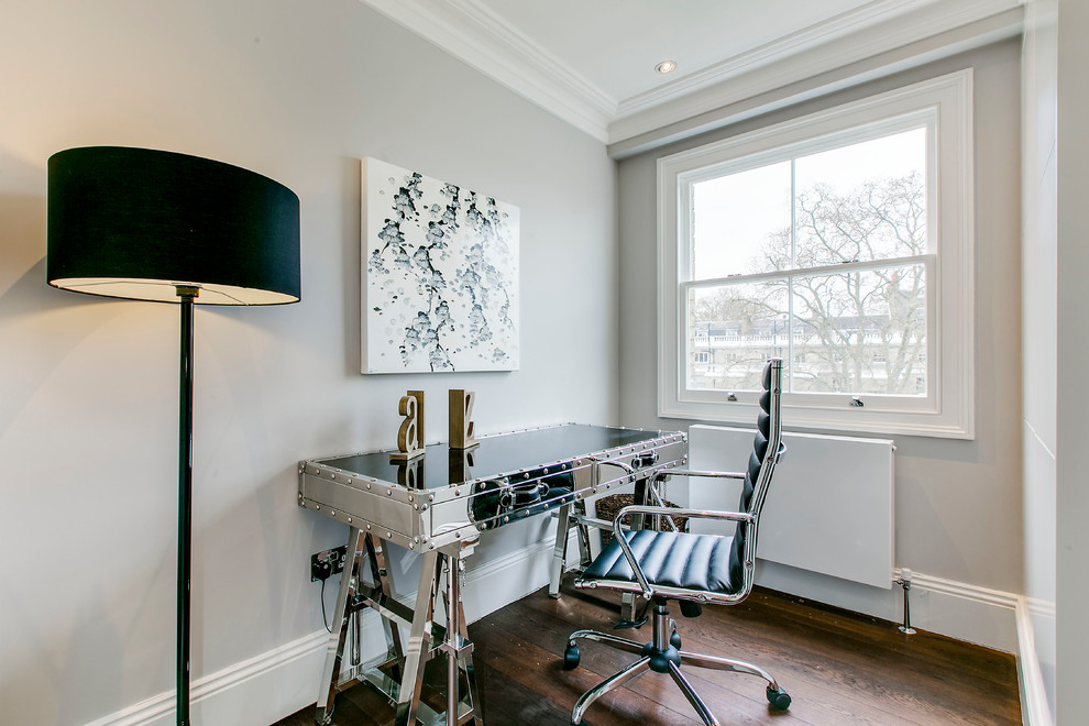Small transitional study room in London with grey walls, dark hardwood floors, a freestanding desk and brown floor.