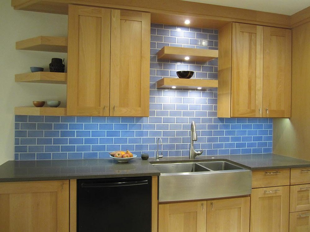 Photo of a mid-sized transitional kitchen in Phoenix with a farmhouse sink, shaker cabinets, light wood cabinets, recycled glass benchtops, blue splashback, subway tile splashback and black appliances.