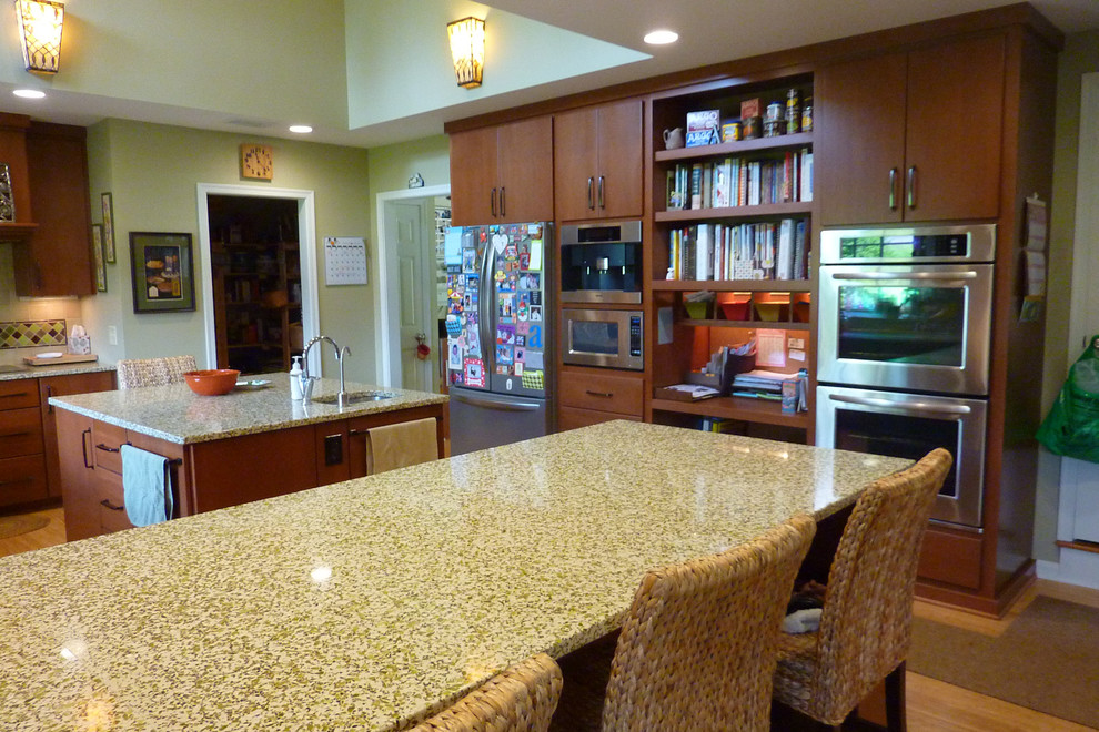 Photo of a large eclectic u-shaped eat-in kitchen in Cincinnati with an undermount sink, flat-panel cabinets, medium wood cabinets, recycled glass benchtops, multi-coloured splashback, stone tile splashback, stainless steel appliances, bamboo floors and with island.