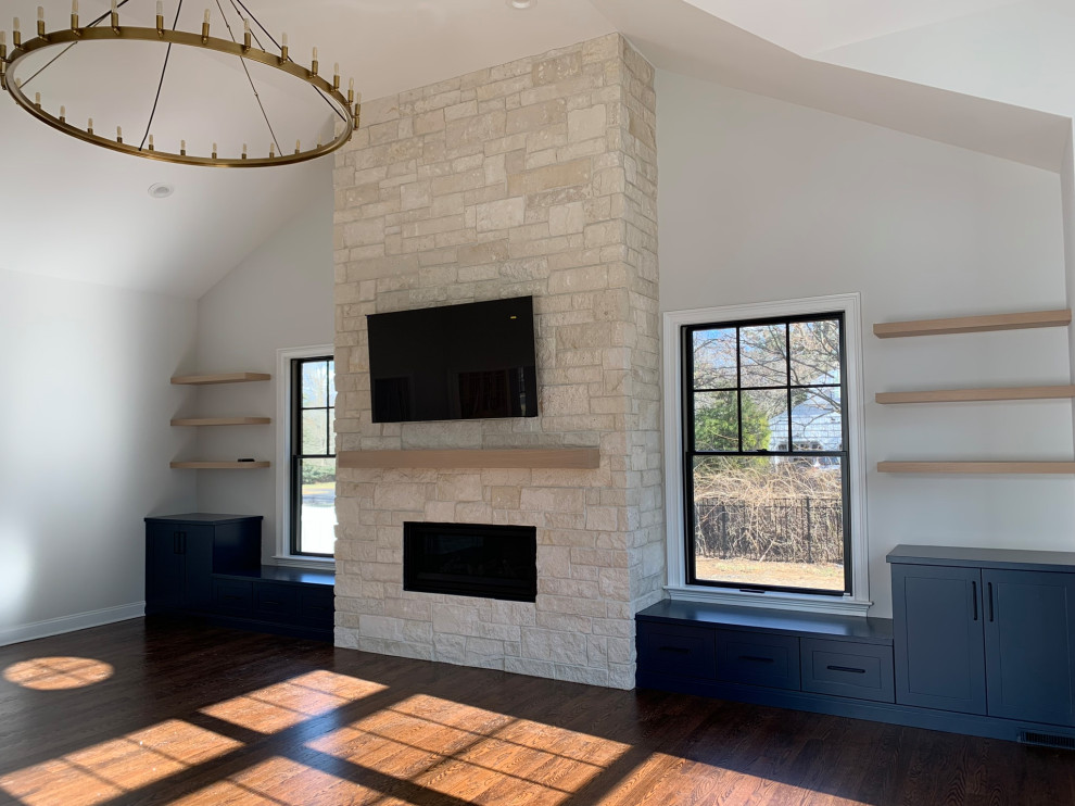 Ejemplo de salón abovedado de estilo de casa de campo con paredes blancas, todas las chimeneas, marco de chimenea de piedra y suelo marrón