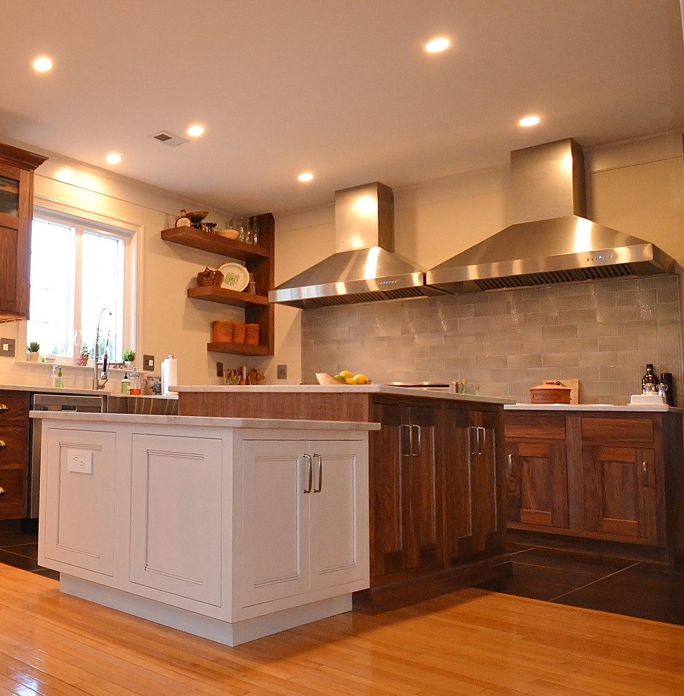 Inspiration for an expansive transitional l-shaped eat-in kitchen in Philadelphia with a farmhouse sink, raised-panel cabinets, medium wood cabinets, quartzite benchtops, grey splashback, subway tile splashback, stainless steel appliances, light hardwood floors, multiple islands, beige floor and white benchtop.