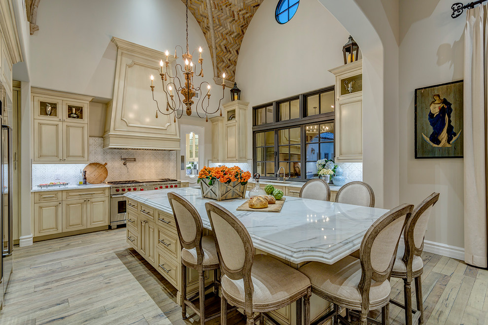 Inspiration for a traditional kitchen in Phoenix with an undermount sink, raised-panel cabinets, beige cabinets, multi-coloured splashback, stainless steel appliances, light hardwood floors, with island, beige floor and marble benchtops.