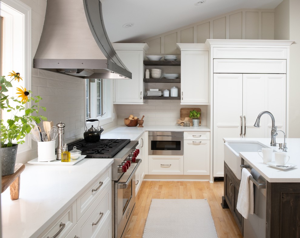 Design ideas for a mid-sized traditional l-shaped kitchen in Minneapolis with a farmhouse sink, flat-panel cabinets, white cabinets, quartz benchtops, beige splashback, subway tile splashback, panelled appliances, light hardwood floors, with island and yellow benchtop.
