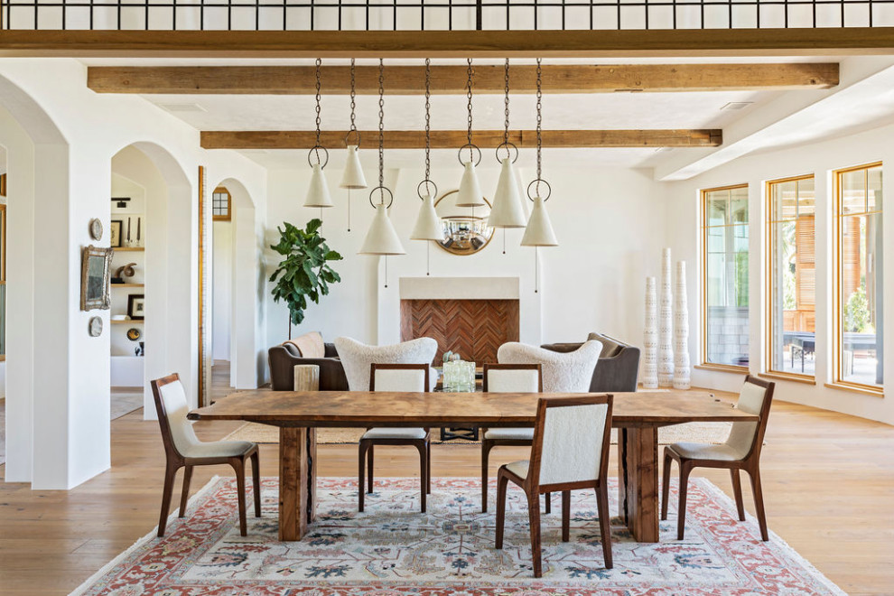 Réalisation d'une très grande salle à manger ouverte sur le salon méditerranéenne avec un mur blanc, parquet clair, un sol marron et poutres apparentes.