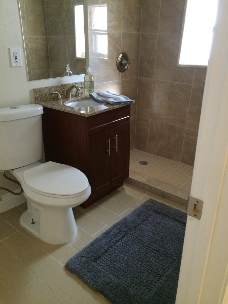 Small traditional bathroom in Miami with a console sink, flat-panel cabinets, dark wood cabinets, granite benchtops, a one-piece toilet, beige tile, ceramic tile, beige walls, ceramic floors, an alcove shower, beige floor and a sliding shower screen.