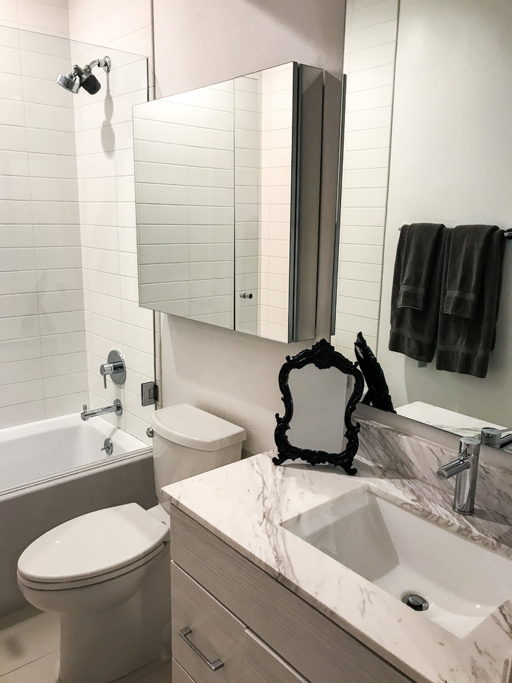 Photo of a small contemporary master bathroom in Los Angeles with glass-front cabinets, a shower/bathtub combo, white tile, subway tile, white walls, ceramic floors, marble benchtops, white floor, a hinged shower door and white benchtops.