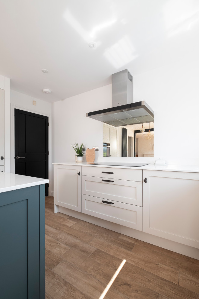 Photo of a medium sized urban u-shaped open plan kitchen in Other with an integrated sink, shaker cabinets, green cabinets, quartz worktops, glass sheet splashback, stainless steel appliances, laminate floors, an island, white worktops and feature lighting.