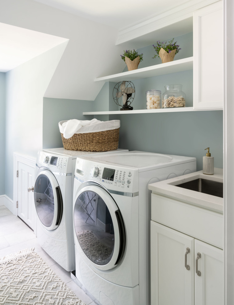 Bild på en vintage vita vitt tvättstuga enbart för tvätt, med en allbänk, skåp i shakerstil, vita skåp, bänkskiva i kvarts, blå väggar, klinkergolv i keramik, en tvättmaskin och torktumlare bredvid varandra och vitt golv