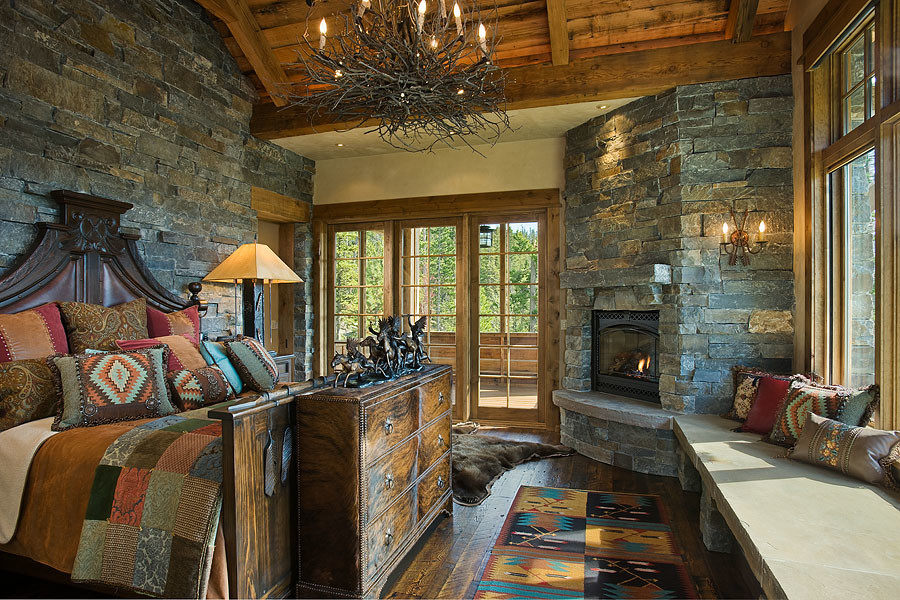 Inspiration for a large country master bedroom in Other with multi-coloured walls, dark hardwood floors, a corner fireplace, a stone fireplace surround and brown floor.