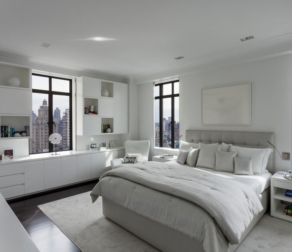 This is an example of a contemporary bedroom in New York with white walls and dark hardwood floors.