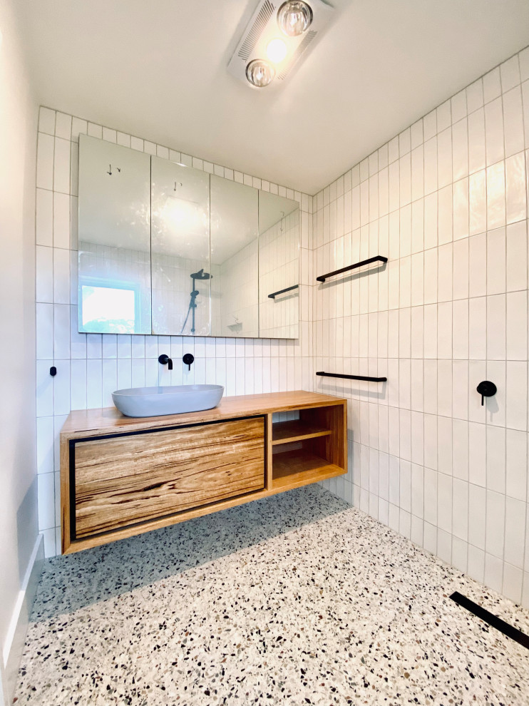 Small trendy white tile and ceramic tile terrazzo floor and single-sink bathroom photo in Other with furniture-like cabinets, medium tone wood cabinets, a one-piece toilet, white walls, a vessel sink, wood countertops, brown countertops and a floating vanity