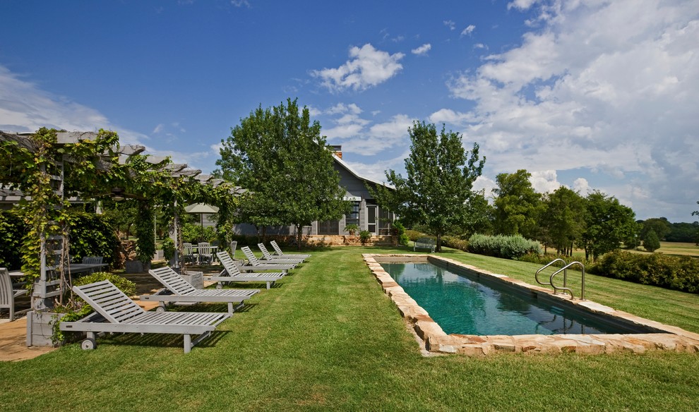 Inspiration for a mid-sized traditional backyard rectangular lap pool in Dallas with natural stone pavers.