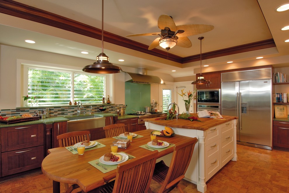 Tropical eat-in kitchen in Hawaii with stainless steel appliances, wood benchtops, a farmhouse sink, glass tile splashback and green benchtop.