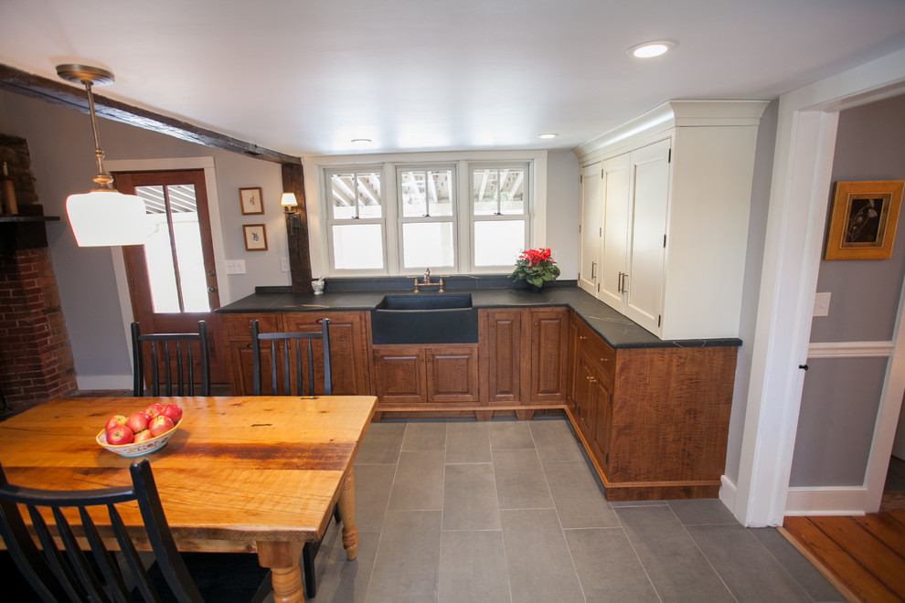 Photo of a mid-sized country l-shaped eat-in kitchen in Philadelphia with a farmhouse sink, soapstone benchtops, stone slab splashback, panelled appliances, porcelain floors and no island.