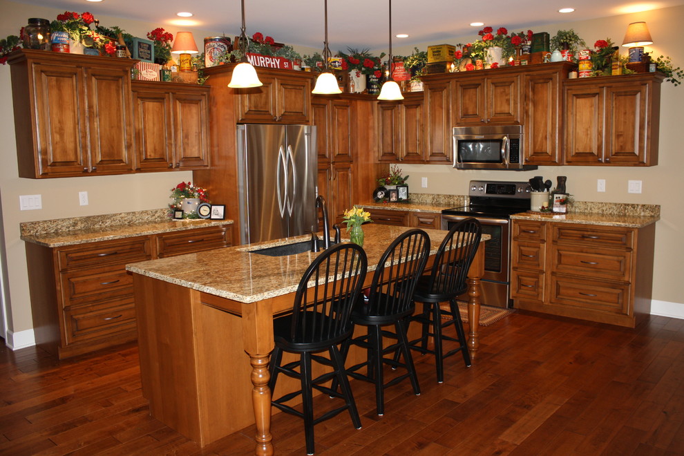 This is an example of a traditional l-shaped eat-in kitchen in St Louis with an undermount sink, raised-panel cabinets, medium wood cabinets, granite benchtops and stainless steel appliances.