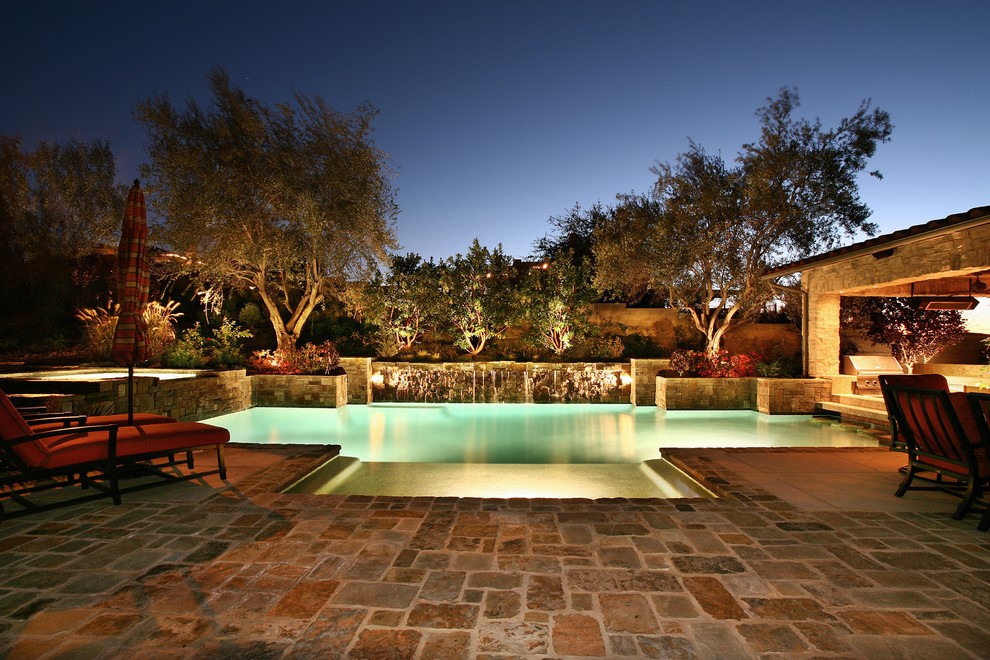 Mid-sized mediterranean backyard custom-shaped pool in Los Angeles with natural stone pavers.