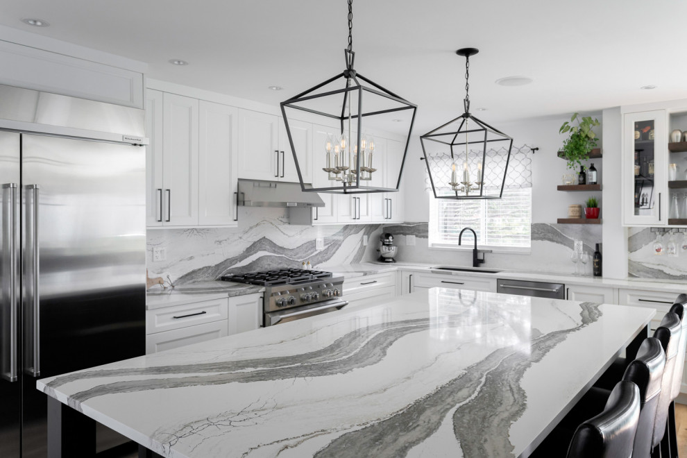 Inspiration for a mid-sized transitional u-shaped medium tone wood floor and brown floor eat-in kitchen remodel with an undermount sink, recessed-panel cabinets, white cabinets, quartz countertops, white backsplash, stone slab backsplash, stainless steel appliances, an island and white countertops