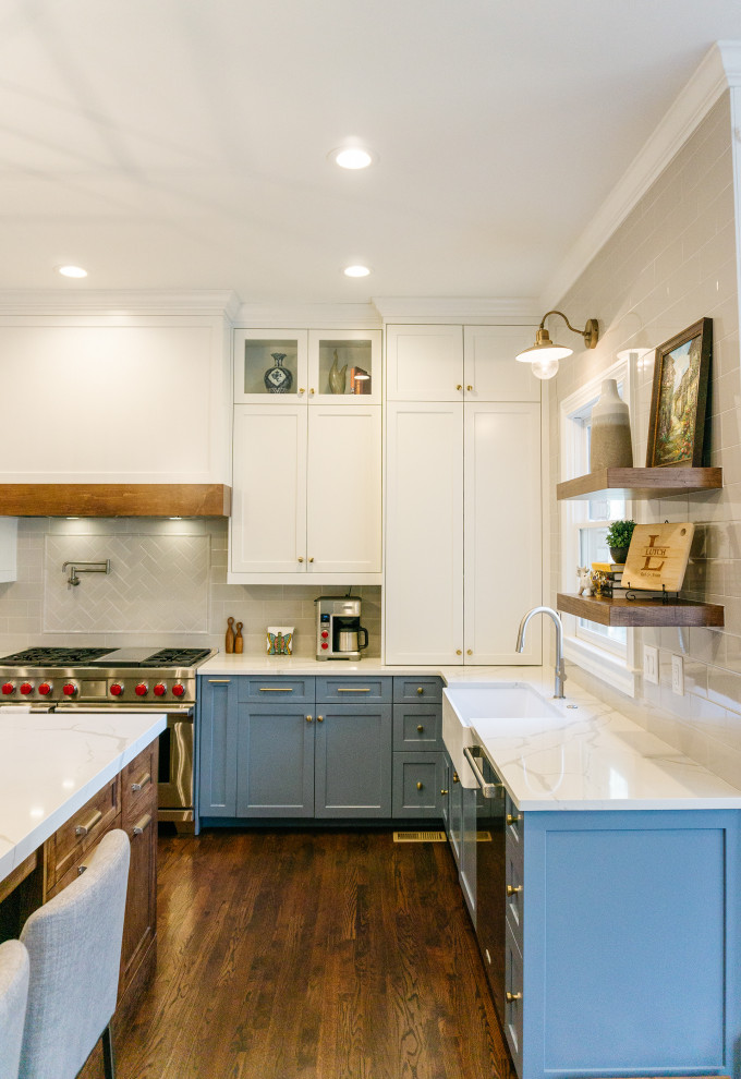 Design ideas for a large transitional u-shaped eat-in kitchen in Atlanta with a farmhouse sink, shaker cabinets, blue cabinets, quartz benchtops, white splashback, porcelain splashback, stainless steel appliances, dark hardwood floors, with island, brown floor and white benchtop.
