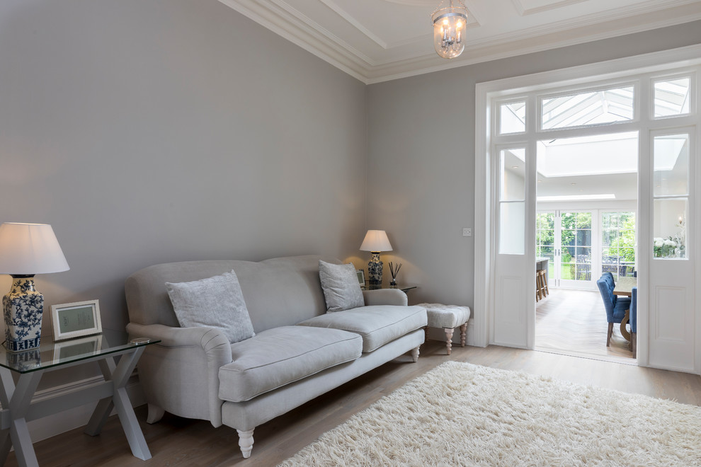 Photo of a mid-sized transitional living room in London with grey walls and light hardwood floors.