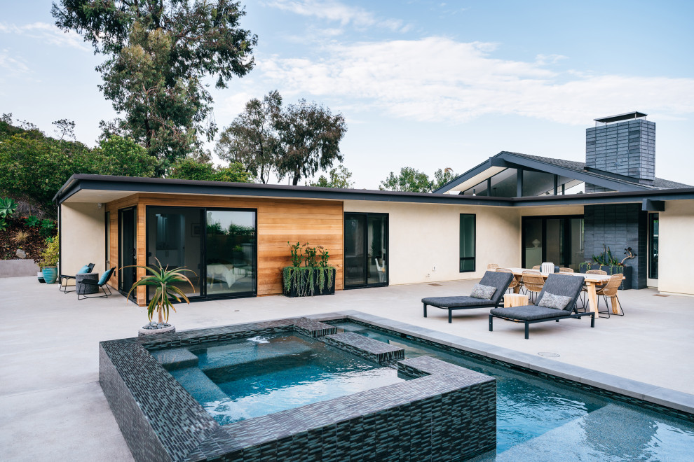 Ispirazione per una piscina moderna rettangolare di medie dimensioni e davanti casa con una vasca idromassaggio e lastre di cemento