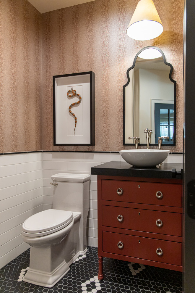 Photo of a transitional powder room in Salt Lake City with flat-panel cabinets, red cabinets, a one-piece toilet, white tile, subway tile, brown walls, mosaic tile floors, a vessel sink, black benchtops, a freestanding vanity and wallpaper.