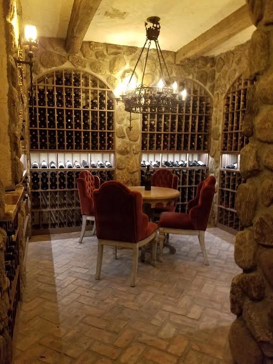 This is an example of a large country wine cellar in Orange County with brick floors, storage racks and brown floor.