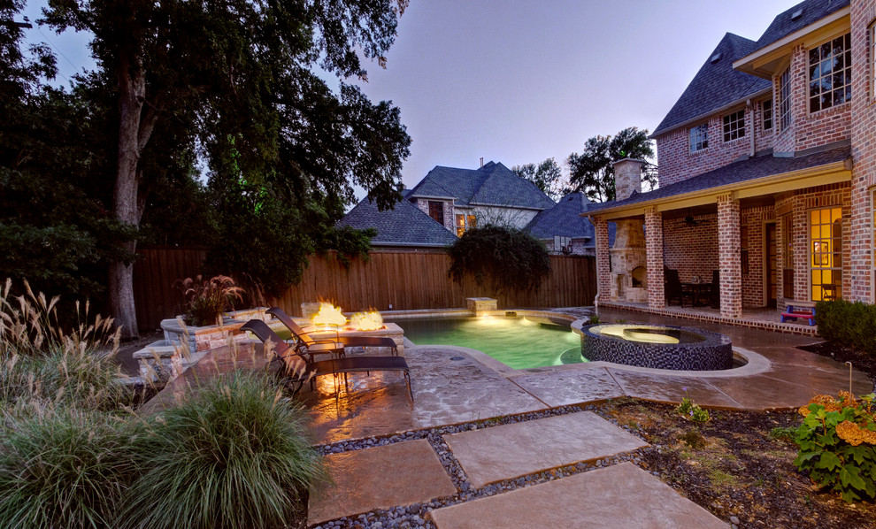 This is an example of a mid-sized contemporary backyard custom-shaped lap pool in Dallas with a hot tub and stamped concrete.