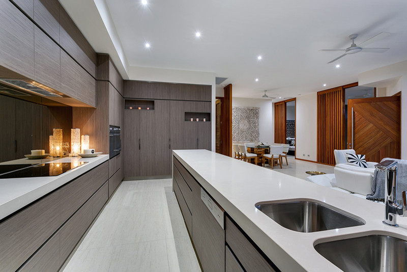 Inspiration for a large tropical galley eat-in kitchen in Cairns with an undermount sink, quartz benchtops, metallic splashback, glass sheet splashback, stainless steel appliances, porcelain floors and with island.