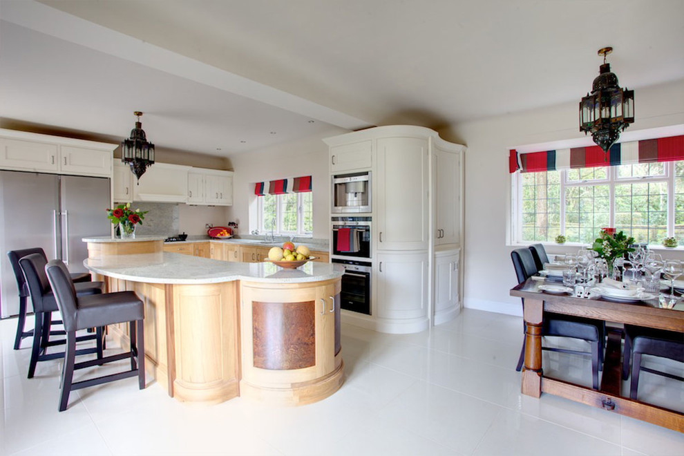 This is an example of a contemporary kitchen/diner in Cheshire with a built-in sink, shaker cabinets, white cabinets, granite worktops, grey splashback, stainless steel appliances, a breakfast bar and grey worktops.