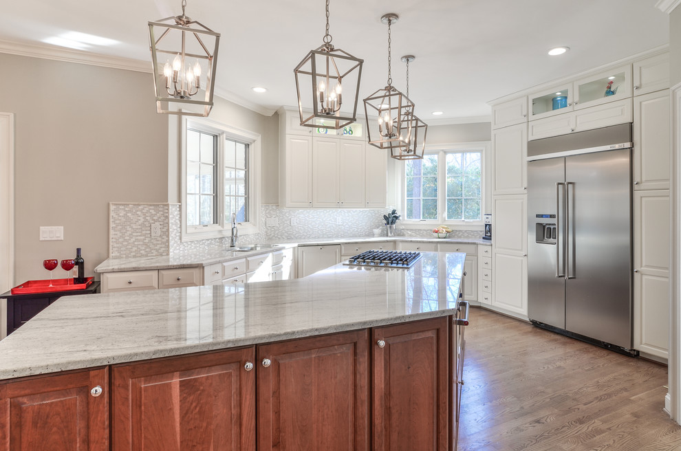 Design ideas for a large traditional kitchen in DC Metro with an undermount sink, raised-panel cabinets, granite benchtops, grey splashback, stainless steel appliances, medium hardwood floors, with island and grey benchtop.