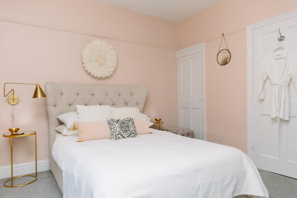 Transitional master bedroom in London with pink walls, carpet and grey floor.
