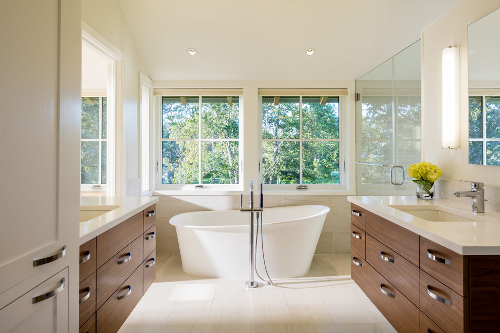 Photo of a contemporary master bathroom in Providence with flat-panel cabinets, medium wood cabinets, a freestanding tub, an undermount sink and a hinged shower door.