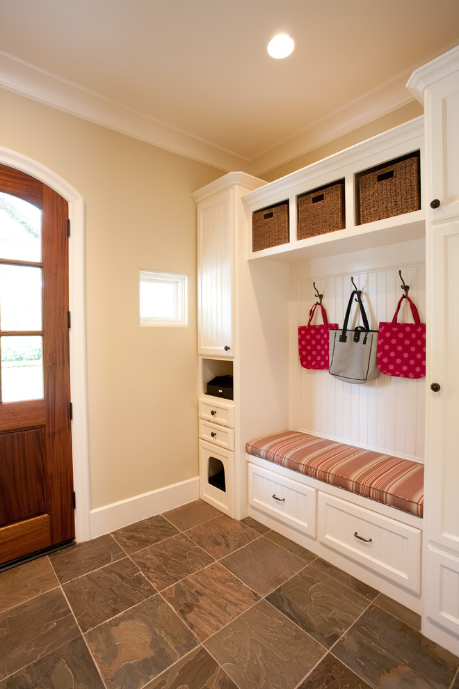 This is an example of a large traditional mudroom in Houston with beige walls, slate floors, a single front door and a medium wood front door.