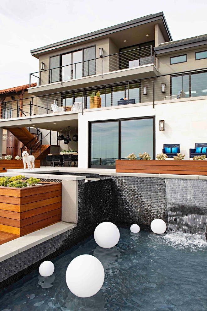 This is an example of an expansive transitional backyard rectangular infinity pool in San Diego with a hot tub and decking.