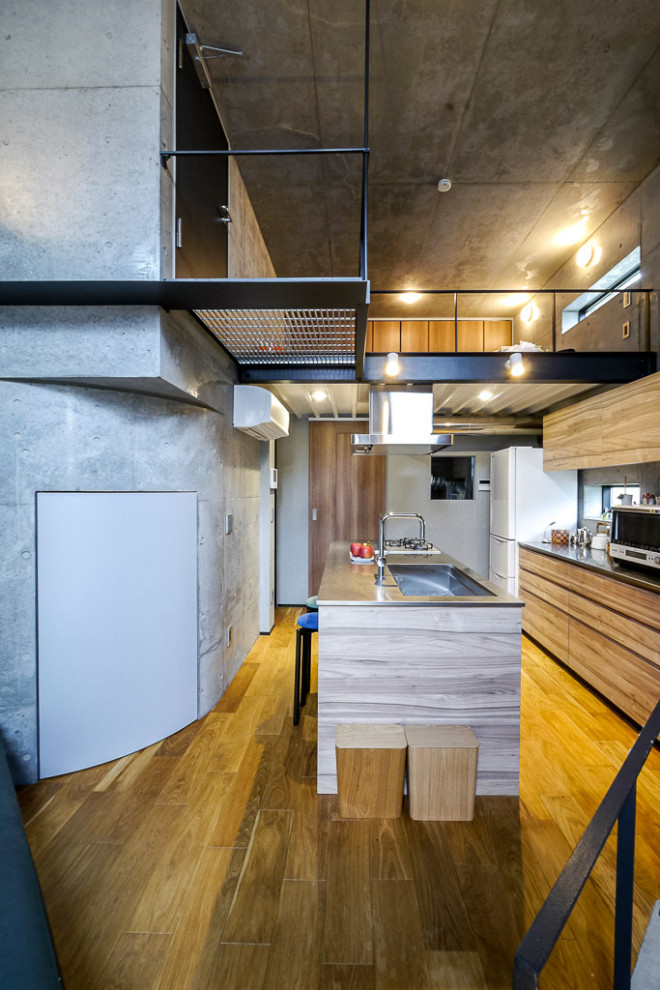 This is an example of a small industrial open plan kitchen in Tokyo with medium hardwood floors and brown floor.