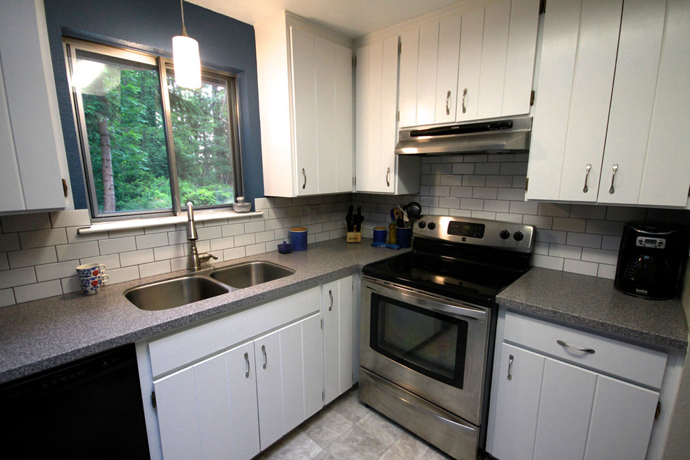 Inspiration for a mid-sized transitional l-shaped linoleum floor enclosed kitchen remodel in Seattle with an undermount sink, flat-panel cabinets, white cabinets, solid surface countertops, white backsplash, subway tile backsplash, stainless steel appliances, blue walls and no island