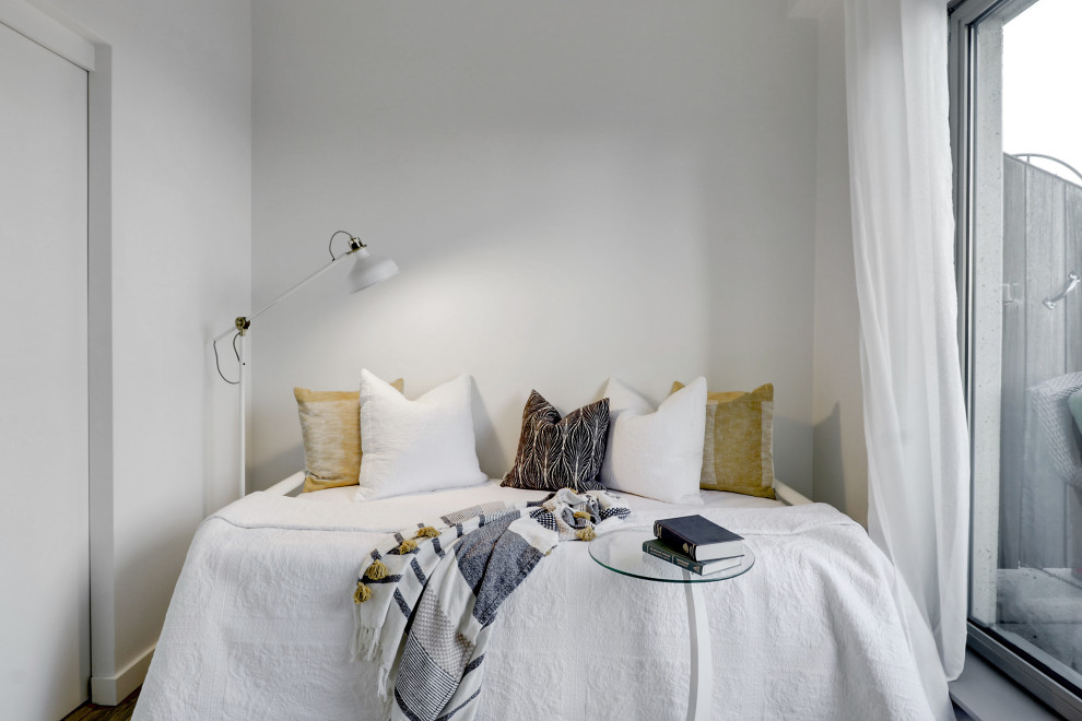 Foto di una piccola camera degli ospiti country con pareti bianche, parquet chiaro, pavimento marrone e soffitto a volta