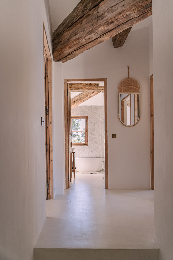 Photo of a mid-sized mediterranean hallway in Other with white walls, concrete floors, beige floor and exposed beam.