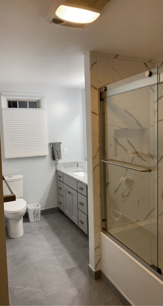 Idées déco pour une salle de bain principale moderne avec un placard à porte shaker, des portes de placard grises, une baignoire en alcôve, WC à poser, un carrelage noir et blanc, du carrelage en marbre, un mur gris, un sol en carrelage de céramique, un lavabo encastré, un plan de toilette en granite, un sol gris, une cabine de douche à porte coulissante, un plan de toilette blanc, une niche et meuble simple vasque.