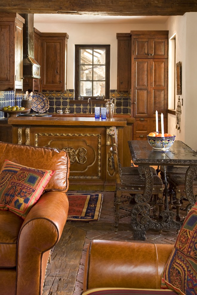Example of a mid-sized mountain style brick floor open concept kitchen design with an undermount sink, raised-panel cabinets, medium tone wood cabinets, wood countertops and mosaic tile backsplash