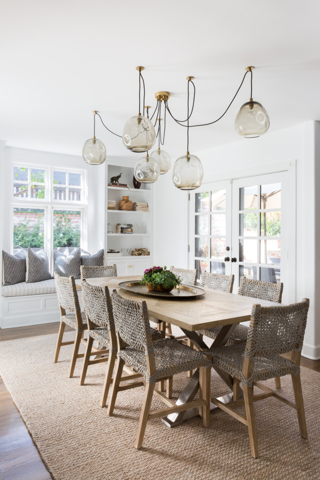 Photo of a beach style dining room in Los Angeles with white walls, dark hardwood floors and brown floor.