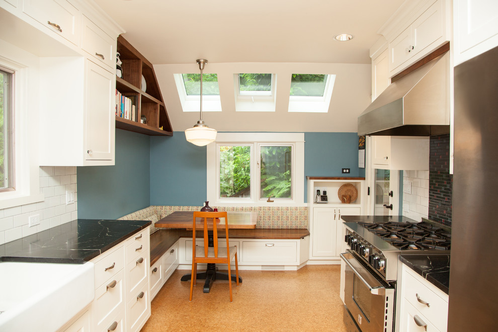 Mid-sized transitional galley eat-in kitchen in Portland with a farmhouse sink, shaker cabinets, white cabinets, soapstone benchtops, yellow splashback, ceramic splashback, stainless steel appliances, cork floors, no island and brown floor.