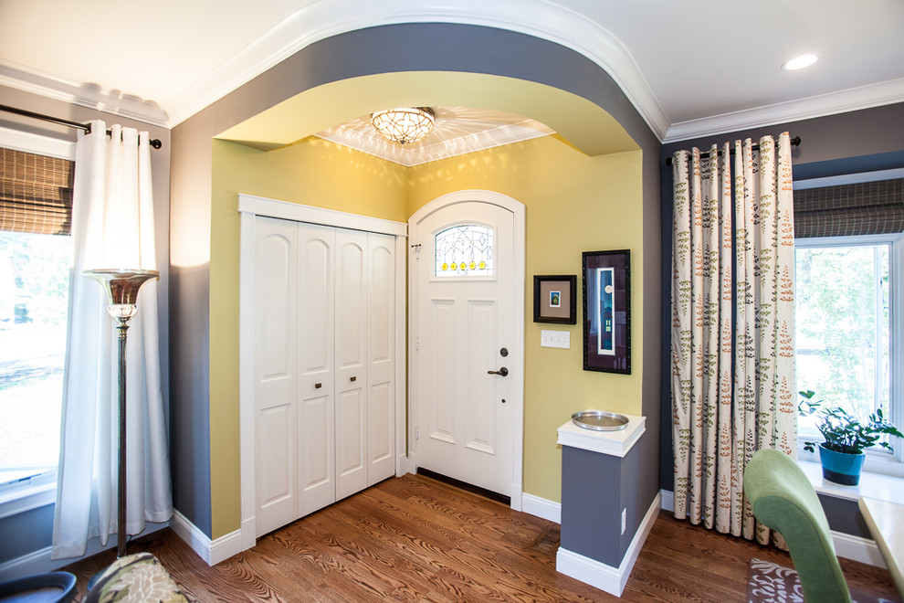 Photo of a small traditional front door in St Louis with yellow walls, dark hardwood floors, a single front door and a white front door.